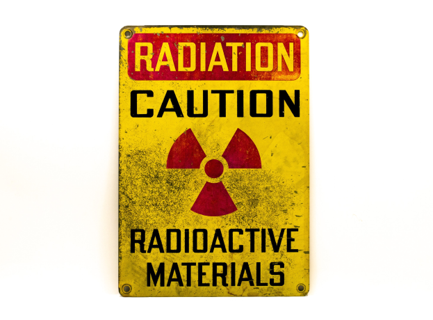 Gelbes Warnschild mit schwarzer Schrift "Strahlungswarnung" und einem radioaktiven Symbol auf einem weißen Hintergrund.