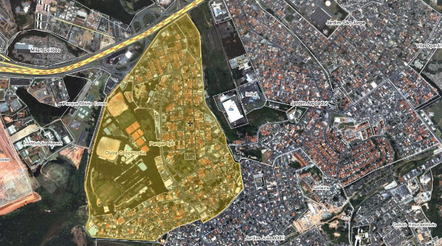 Luftaufnahme einer Stadt mit Gebäuden, Straßen, Bäumen und Gras, die eine zentrale Karte eines geplanten Entwicklungsstandorts zeigt.