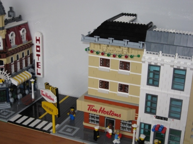 Spielzeuggebäude auf der rechten und linken Seite des Bildes, ein Schild auf der linken Seite und kleine Spielzeuge unten.