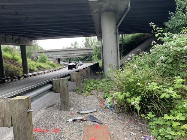 Auto fährt unter einer Brücke mit Trömmern auf der Seite der Straße, umgeben von Bäumen und einem klaren Himmel, wahrscheinlich die Nachwirkung eines tödlichen Unfalls auf dem I-95.