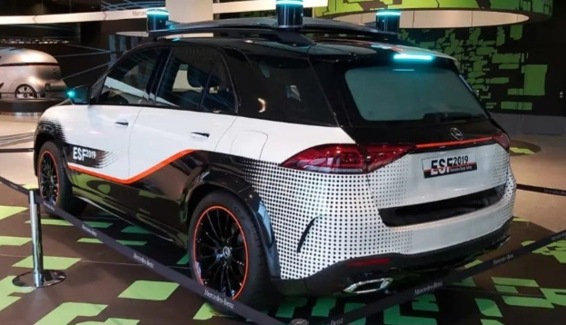 Mercedes-Benz E-Klasse Electric SUV auf der IAA in Frankfurt gezeigt, umgeben von Absperrpollern mit Seilen und Lichtern, mit einem weiteren Fahrzeug und einer textbedruckten Wand im Hintergrund.