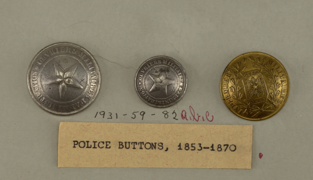 Drei silberne Polizeimarke mit Text darauf auf einer weißen Oberfläche platziert.