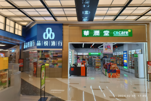 Das Innere eines Ladens namens "CRCare" mit einer Person vor einem Schild, Regalen mit Gegenständen, Tafeln mit Text, Deckenleuchten und verstreuten Gegenständen, mit einem Wasserzeichen unten.