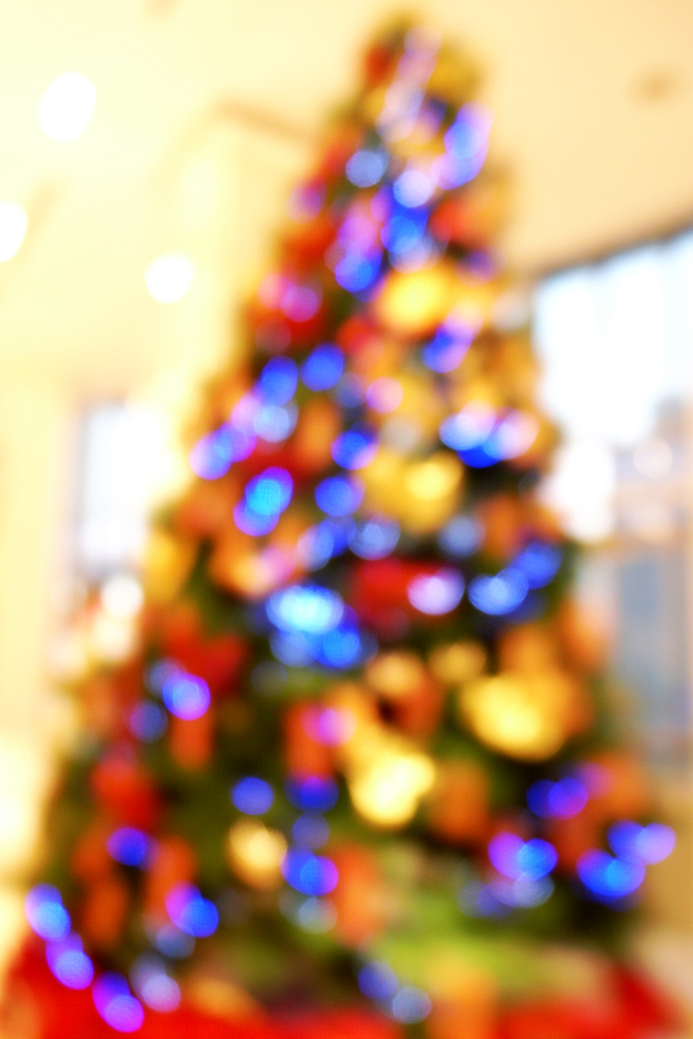 Ein unscharfer Innenraum mit einem Weihnachtsbaum in der Mitte, der mit Lichtern und Schmuck verziert ist.