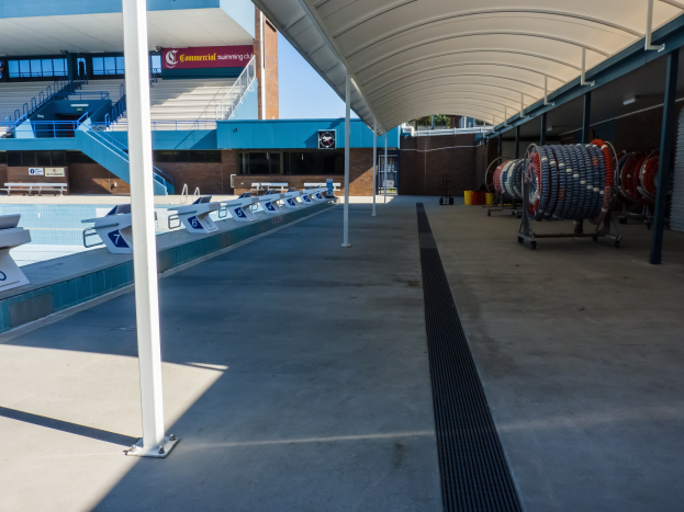 Großes Hallenbad an der University of Texas at Austin mit zahlreichen Stühlen auf der Poolterrasse, mehreren Pfählen auf der linken Seite und verschiedenen Gegenständen auf der rechten Seite.