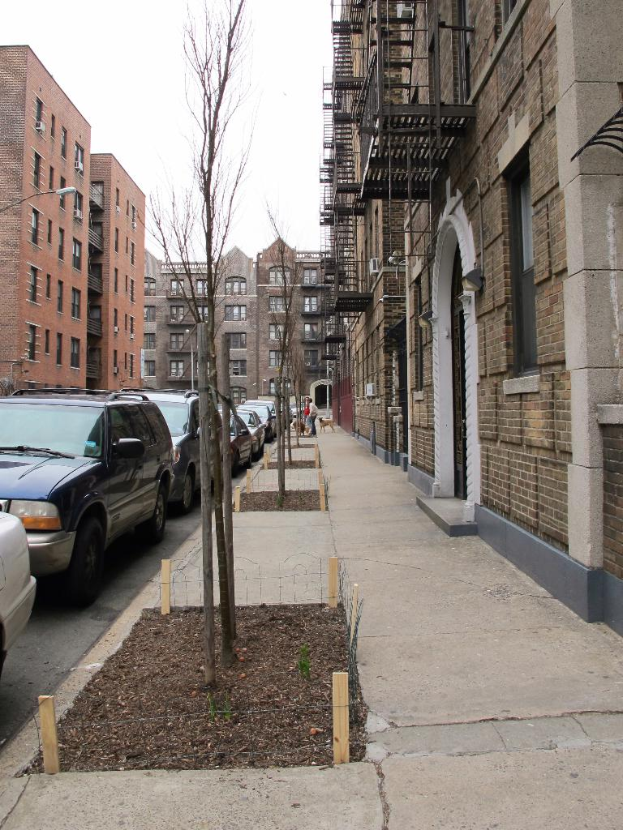 Eine spärliche Stadtansicht mit ein paar Autos und Gebäuden in der rechten Ecke und ein paar anderen Gebäuden in der linken Ecke.