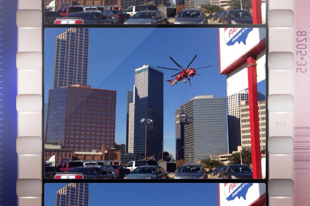 Ein Brett, auf dem Fahrzeuge auf der Straße, Gebäude und ein Flugzeug am Himmel zu sehen sind.