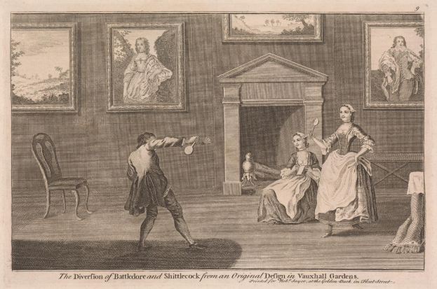 Zwei Personen spielen Tischtennis in einem Raum mit Kamin, Stühlen und gerahmten Fotos an der Wand.