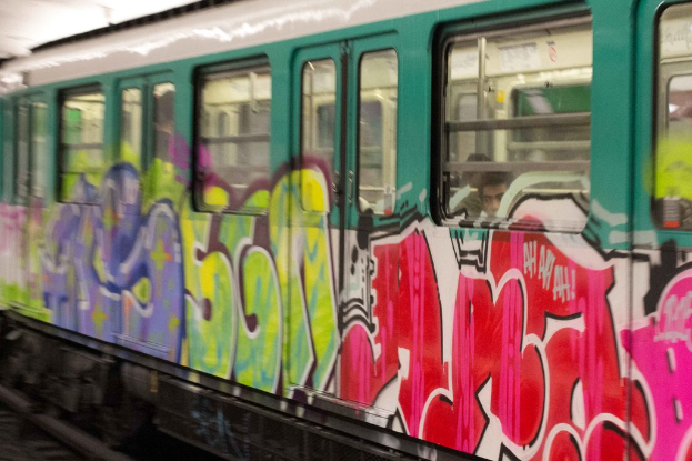Ein Zug auf Eisenbahnschienen mit zwei Personen darin und Graffiti äußerlich.