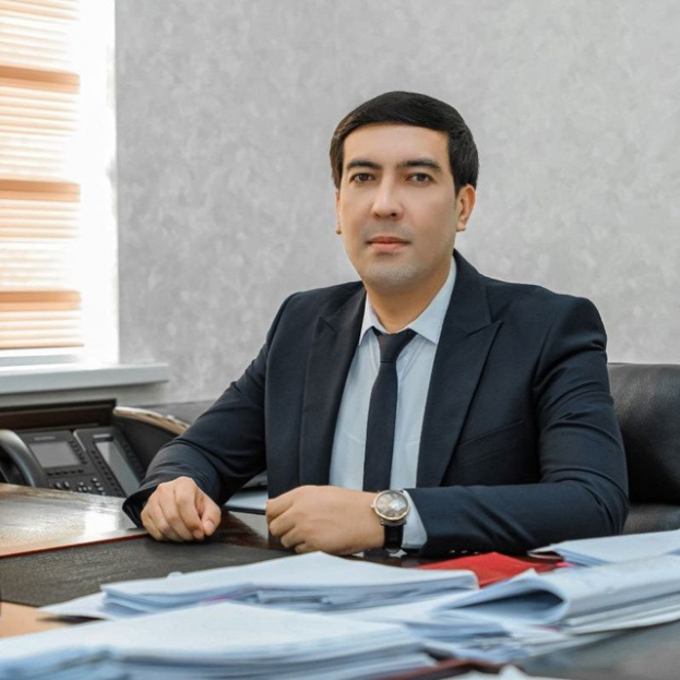 Ein Mann in einem Anzug sitzt an einem unordentlichen Schreibtisch in einem Büro, mit Papieren, einem Telefon und anderen Gegenständen, die über die Oberfläche verstreut sind, und sieht ernst aus.