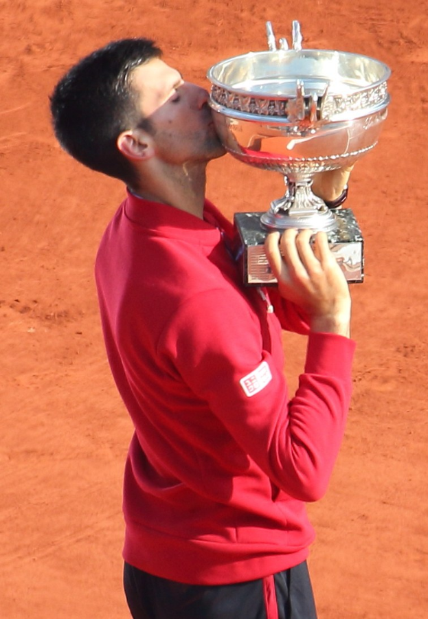 Novak Djokovic hält den French-Open-Pokal nach dem Sieg gegen Rafael Nadal im Finale der Herren-Einzelkonkurrenz und feiert mit einem triumphierenden Gesichtsausdruck.