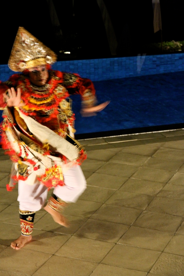 Eine Person läuft, geschmückt mit Kränzen, einer Krone und verschiedenen Kleidungsstücken.