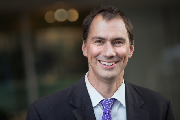 Ein Mann im Anzug lächelt.