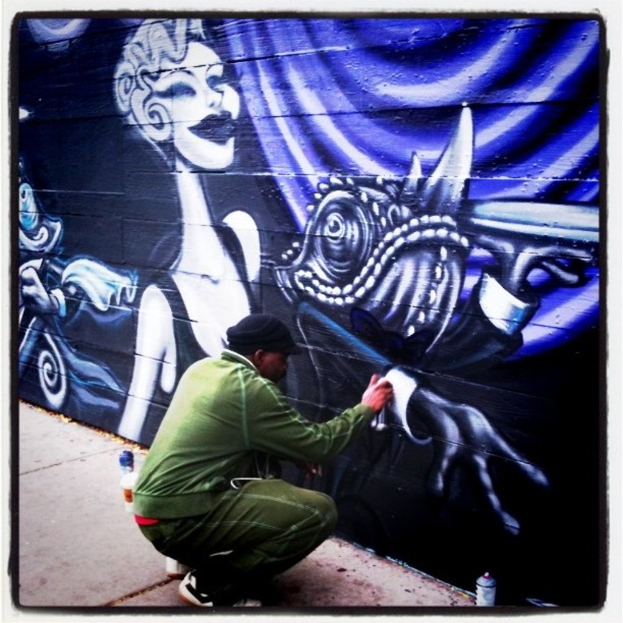 Eine Person mit einer Flasche in der Hand, umgeben von anderen Flaschen auf der Straße, Graffiti an einer Wand im Hintergrund.