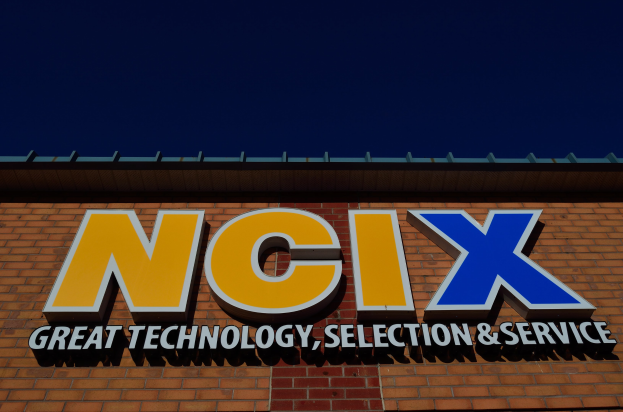 Brick building with a sign reading "NCIX Great Technology, Selection & Service" under a clear blue sky.