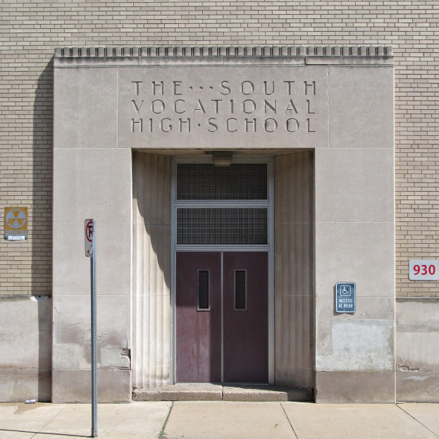 Das Südliche Berufsschulgebäude mit einer Tür und Schildern, mit einem Weg, der zur Eingangstür führt.