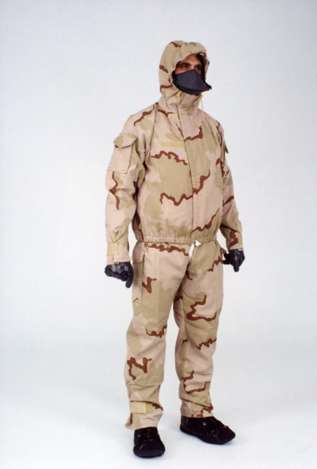 Eine Person in einem camouflage-musternden Schutzoverall und Kapuze steht vor einem weißen Hintergrund.