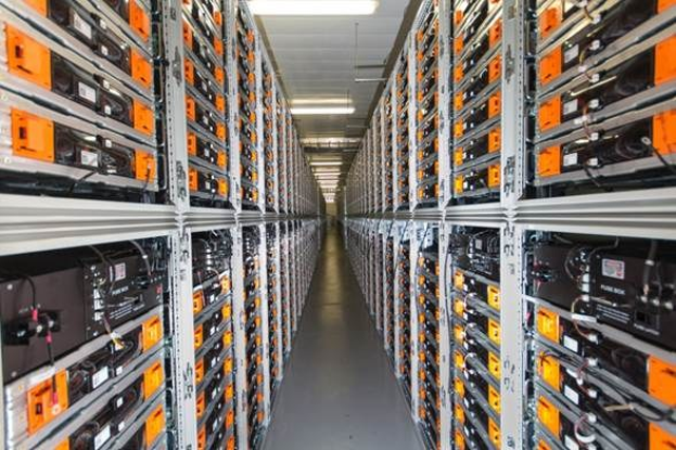 Eine lange Reihe von Servern in einem Rechenzentrum mit elektronischen Geräten in Gestellen und Anzeigelampen oben.