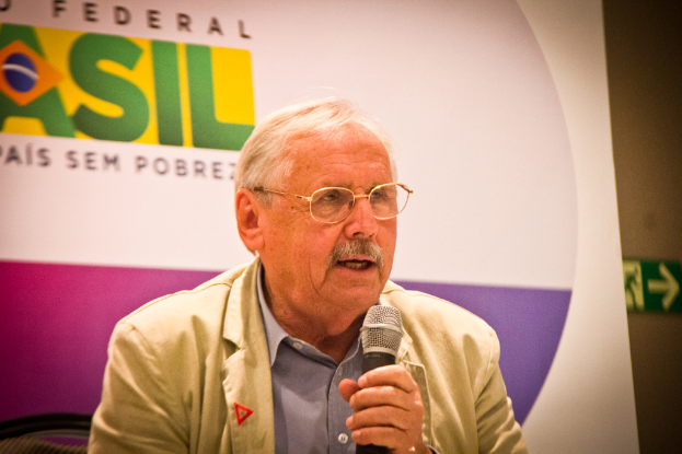 Eine Person, die in ein Mikrofon spricht, mit einem Banner im Hintergrund, auf dem das Wort 'Bundes' steht.