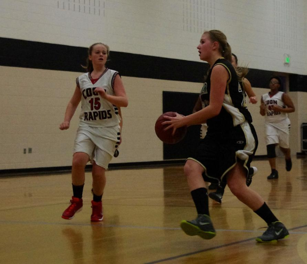 Eine Gruppe von Menschen spielt Basketball in einem Raum mit einer Wand im Hintergrund.