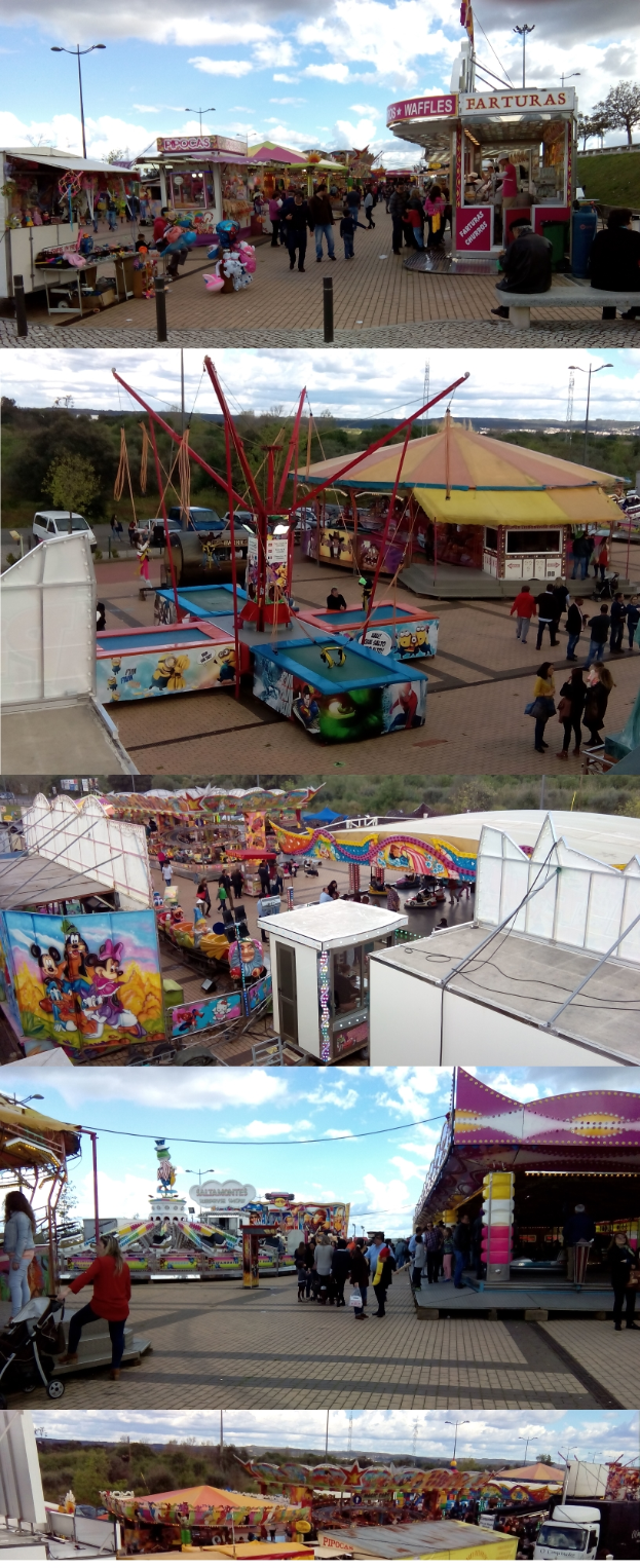 Eine KarnevalsSzene mit Menschen, die herumstehen, umgeben von Buden, Fahrgeschäften, Mästchen, Lichtern, Bäumen und einem bewölkten Himmel.