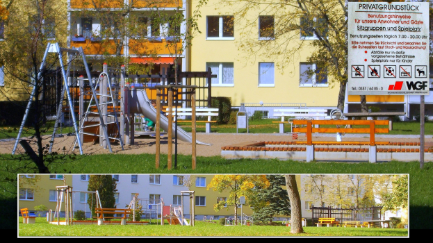 Ein Spielplatz mit einer Rutsche und Schaukeln vor einem Gebäude, umgeben von Bäumen, Gras, Bänken und anderen Gegenständen, mit einer Tafel mit Text im Hintergrund.