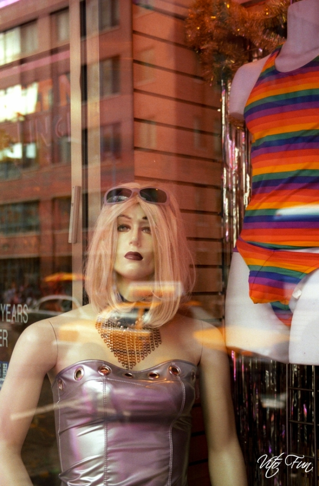 Eine Schaufensterpuppe mit Brille steht vor einem Gebäude.