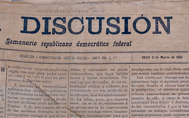 Eine gelbliche, leicht zerknitterte Zeitung mit der schwarzen Schrift 'Diskussion' darauf, die die Schlagzeile 'Semanario Repúblicano Democrático Federal' trägt.