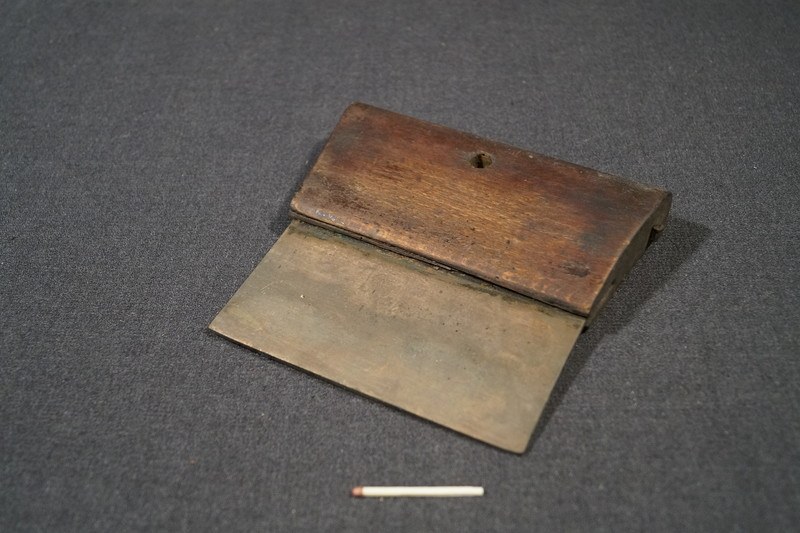 Kleines hölzernes Streichholzschächtelchen mit offenem Deckel, enthaltend eine einzelne Zigarette, die auf einer schwarzen Oberfläche neben einer ausgepackten Zigarette liegt.