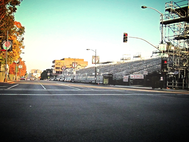 Eine Straße mit einem Verkehrszeichenmast und Gerät auf der rechten Seite, Warnschilder und mehrere Fahrzeuge auf der linken Seite und Bäume im Hintergrund.