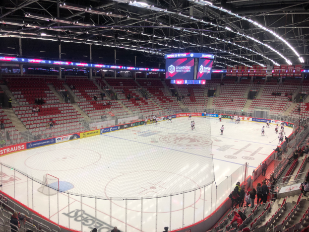 Ein Eishockeyspiel in einer großen Arena mit Zuschauern, einem Zaun um die Eisfläche, einem Bildschirm mit der Aufschrift "St. Louis Blues vs Detroit Red Wings", Metallrahmen und einer Decke mit Deckenbeleuchtung.