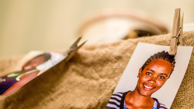 Auf einem Tisch liegt eine Klammer, ein Passfoto im Passformat und ein Stoffstück auf der rechten Seite, mit einem unscharfen Hintergrund und linker Seite.