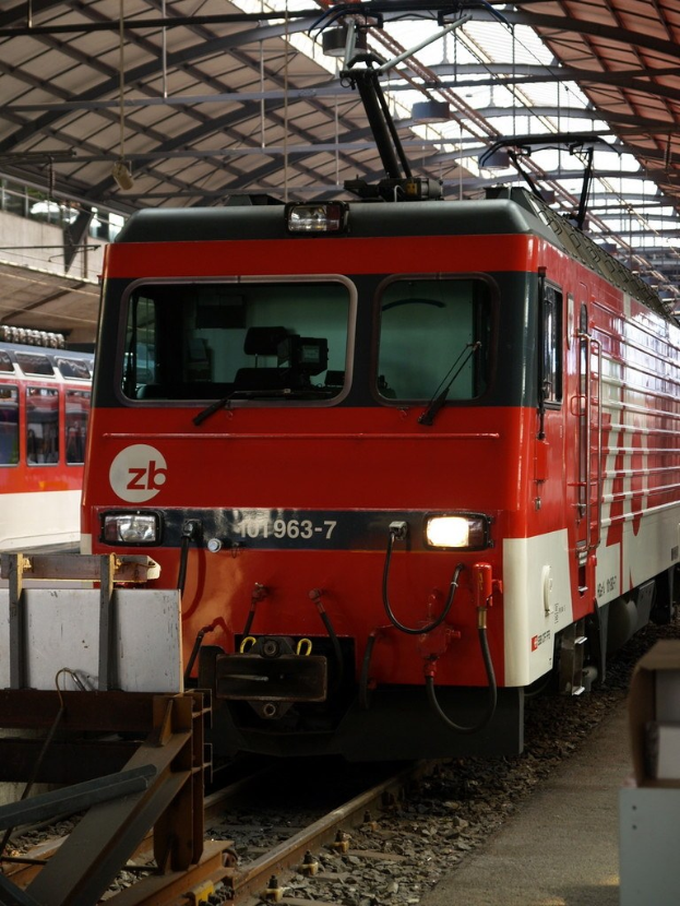 Ein Zug fährt auf einem Gleis mit Steinen und Stangen in der Nähe, auf dessen Seite Text angezeigt wird.