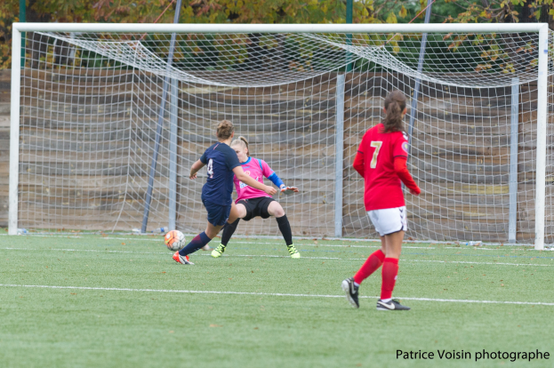 Eine Gruppe von Frauen, die auf einem Rasenfußballfeld mit Bäumen im Hintergrund und einem Tor spielt, mit Text unten.