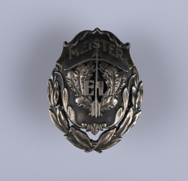 Ein silbergerändertes Abzeichen mit einem Lorbeerkranz, das die deutsche Armee repräsentiert, mit einer Inschrift.