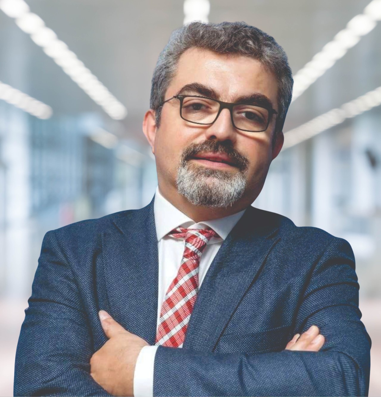 Porträt eines Mannes in Anzug und Krawatte mit verschränkten Armen, der eine Brille trägt und vor einem unscharfen Hintergrund steht, mit Text, der ihn als neu ernannten Marketingchef ausweist.