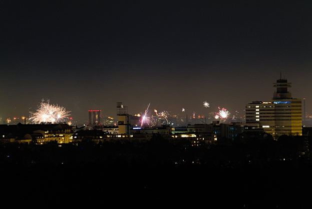Eine nächtliche Stadt Silhouette, erleuchtet von Feuerwerk und bunten Lichtern an den Gebäuden.