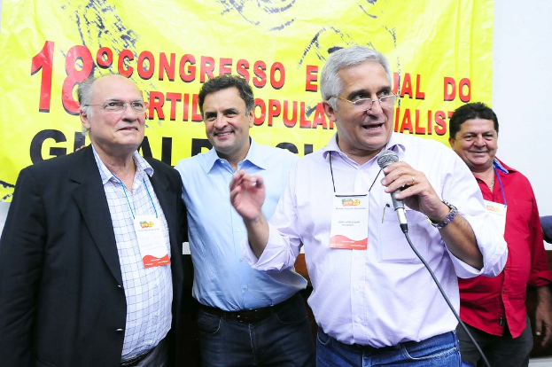 Ein Mann spricht in ein Mikrofon vor einem gelben Vorhang mit der Aufschrift "18-Grad-Kongress O"