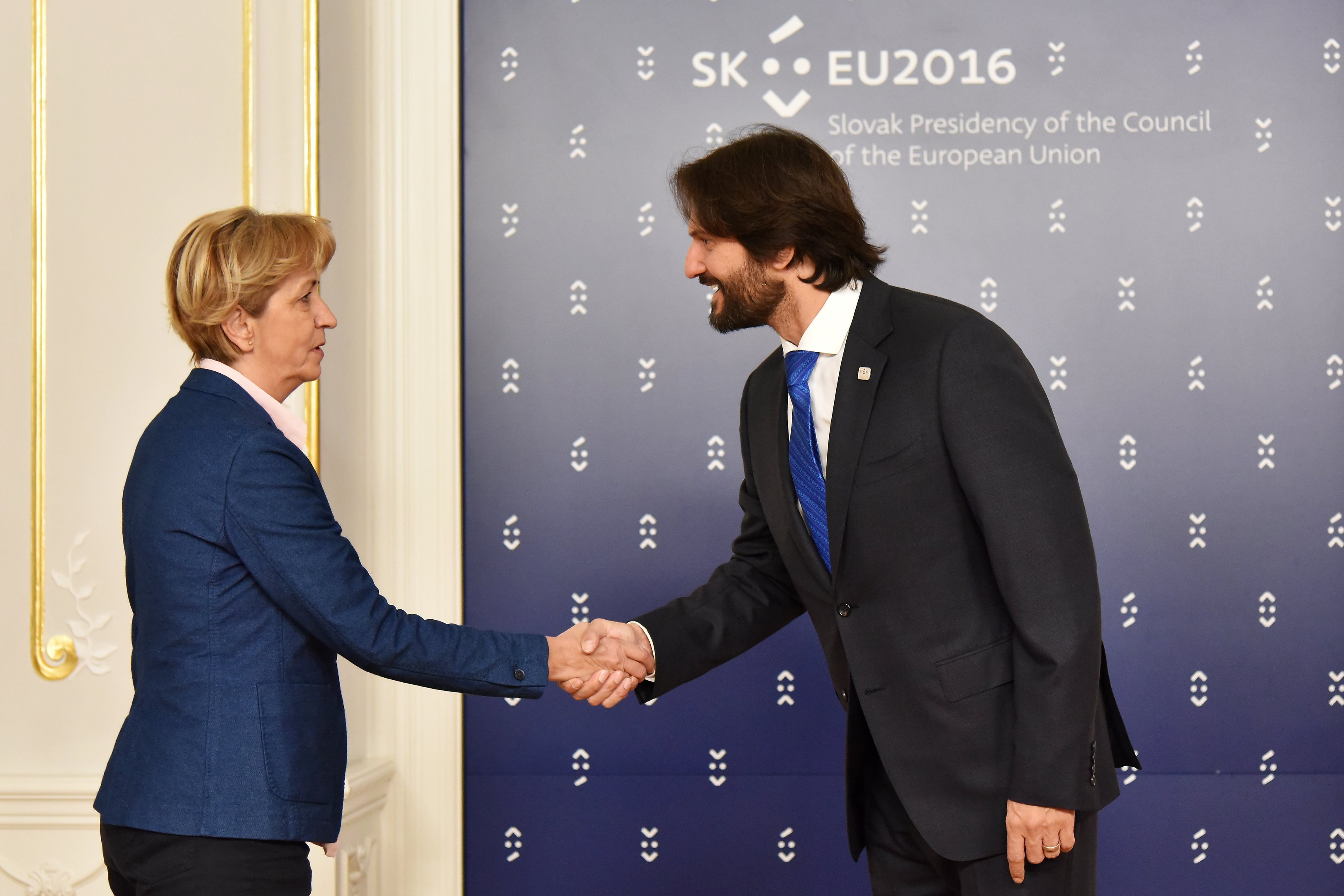 Bundeskanzlerin Angela Merkel und Joachim Gauck geben sich die Hand bei einem EU-Gipfeltreffen und lächeln beide.