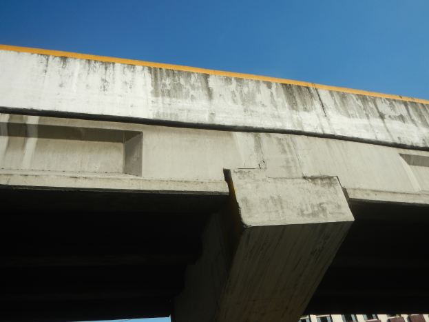 Eine Betonbrücke im Bau mit blauem Himmel und einem Gebäude unten.