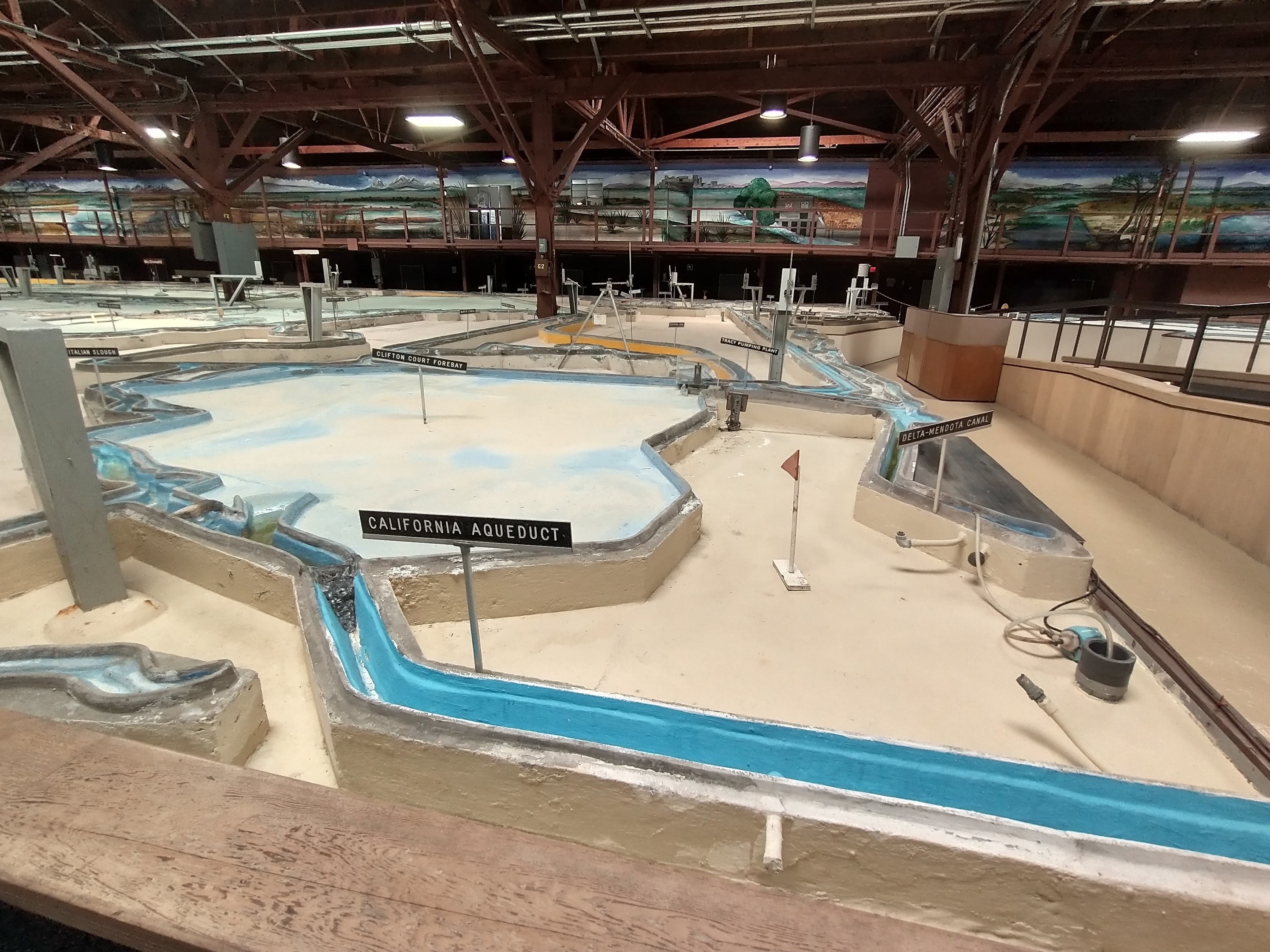 Indoor-Wasserpark mit mehreren Wasserrutschen, Deckenbeleuchtung, Wandgemälden und einem Minigolfplatz mit Beschilderung.